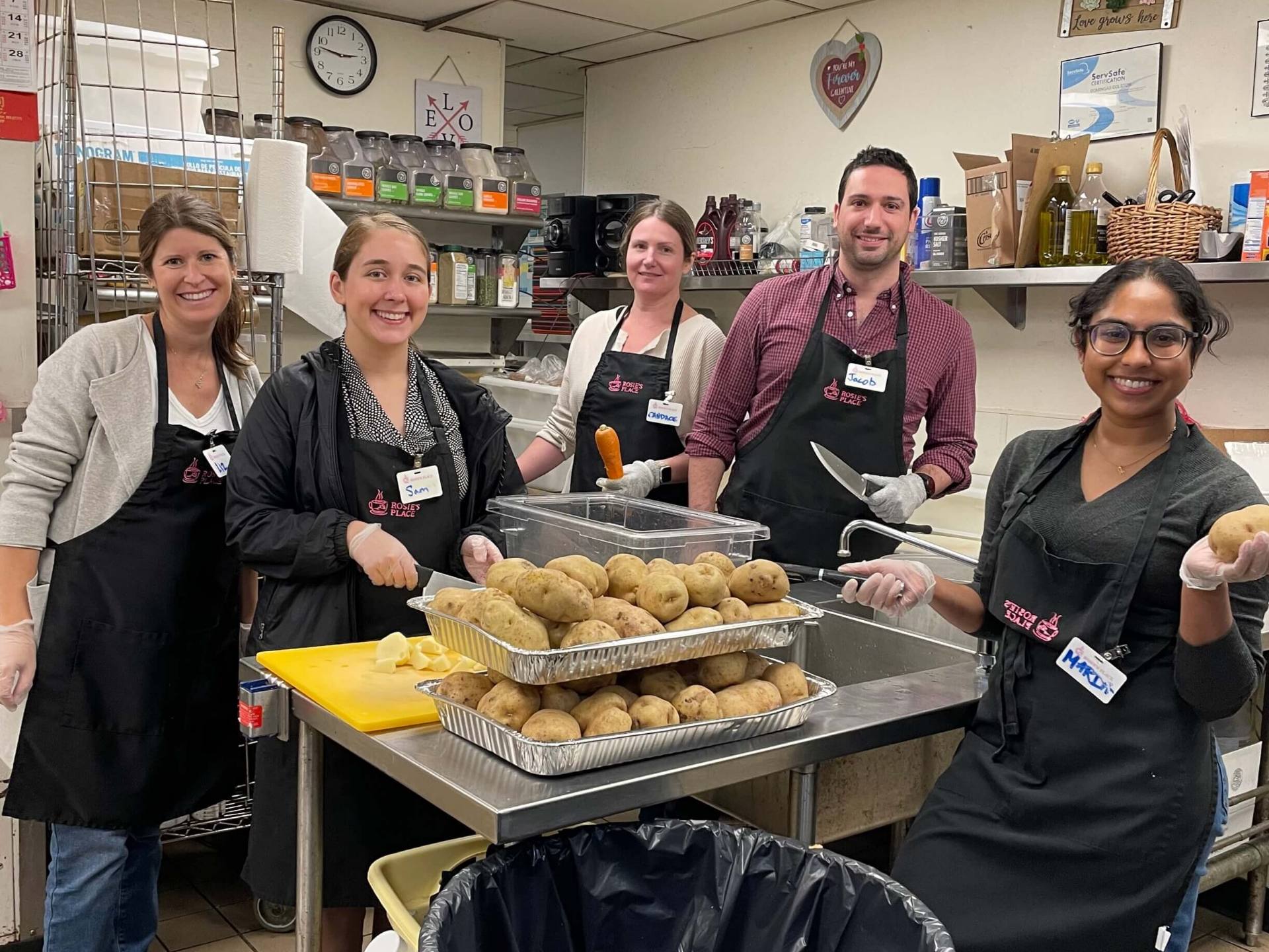 A group of volunteers in a kitchen, engaged in preparing meal, highlighting a warm and communal atmosphere.