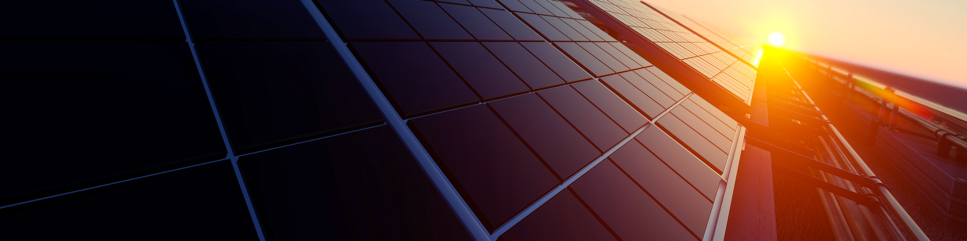 A row a tilted solar panels against a vibrant sunset, casting warm hues across the sky.