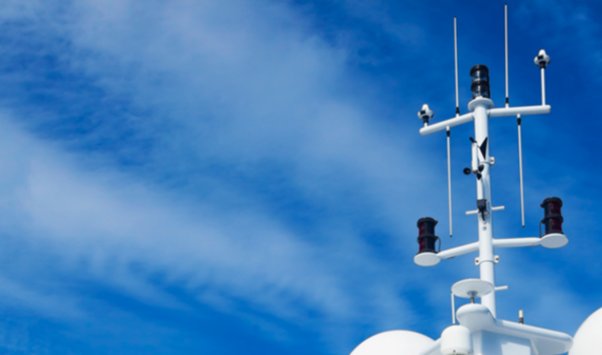 A white ships mast with antennas stands against a clear blue sky, showcasing a serene and open atmosphere.