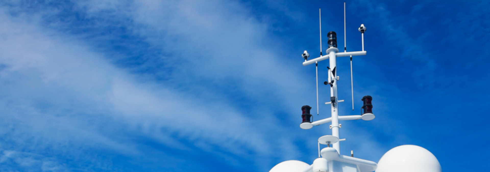 A white ships mast with antennas stands against a clear blue sky, showcasing a serene and open atmosphere.