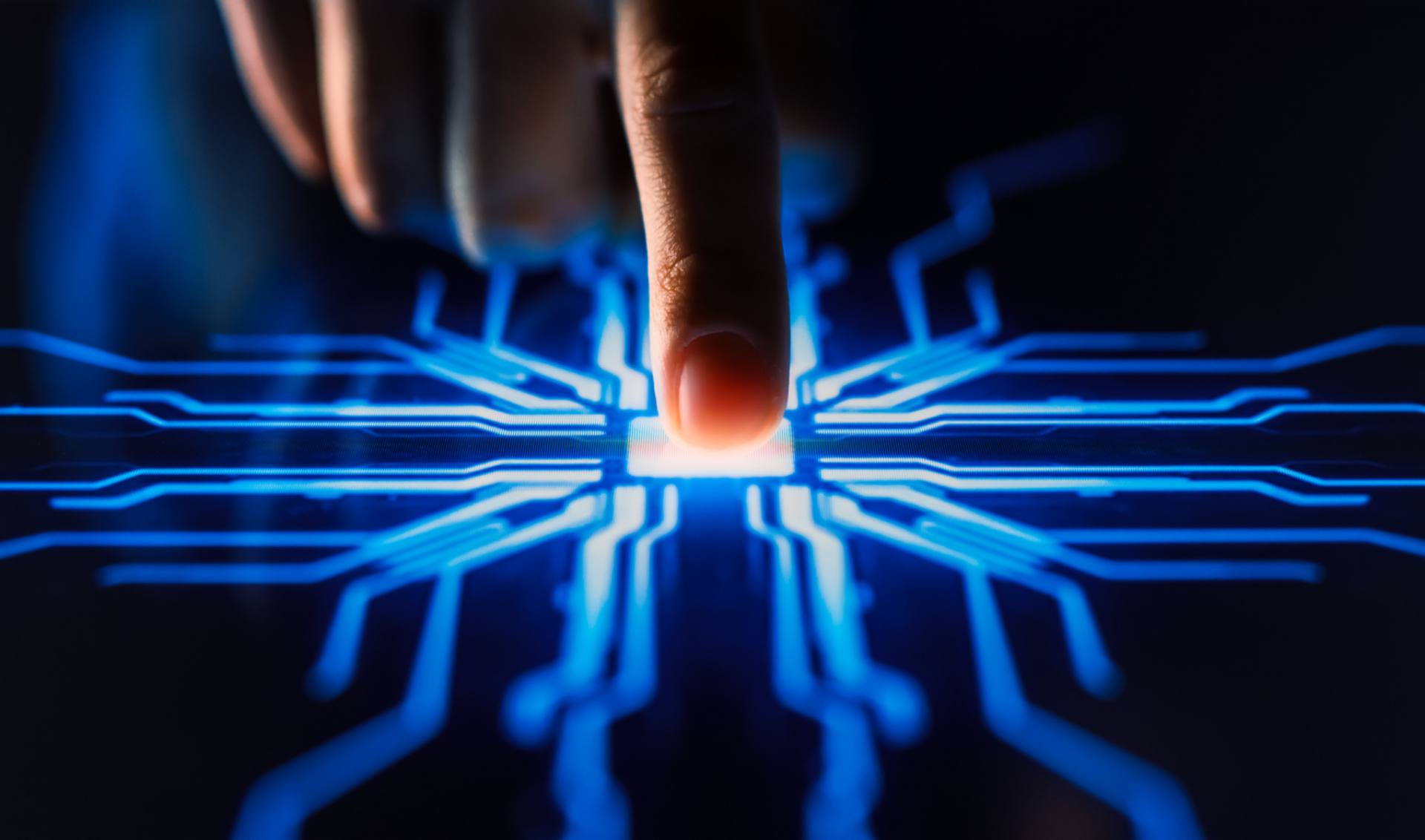 A close-up of a hand activating a button on a circuit board, showcasing the connection between human and technology.