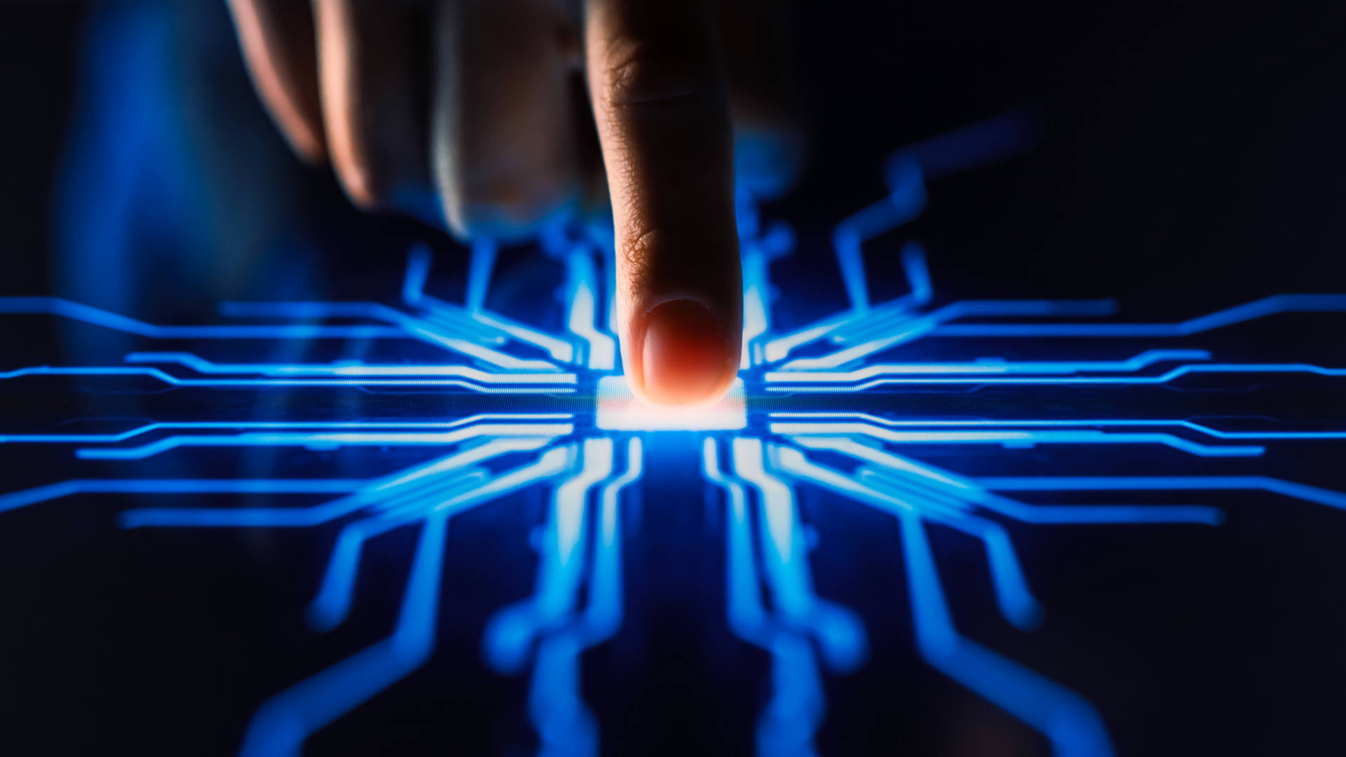 A close-up of a hand activating a button on a circuit board, showcasing the connection between human and technology.