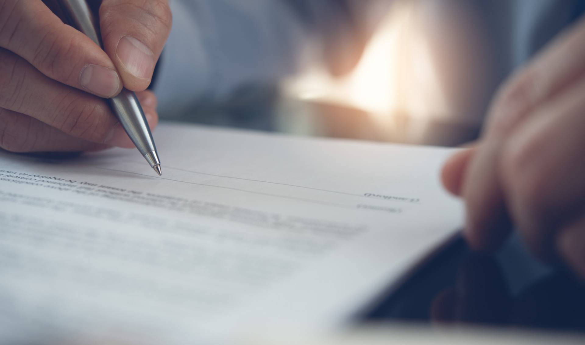 A man engaged in signing a contract with a pen, representing the finalization of an important document.