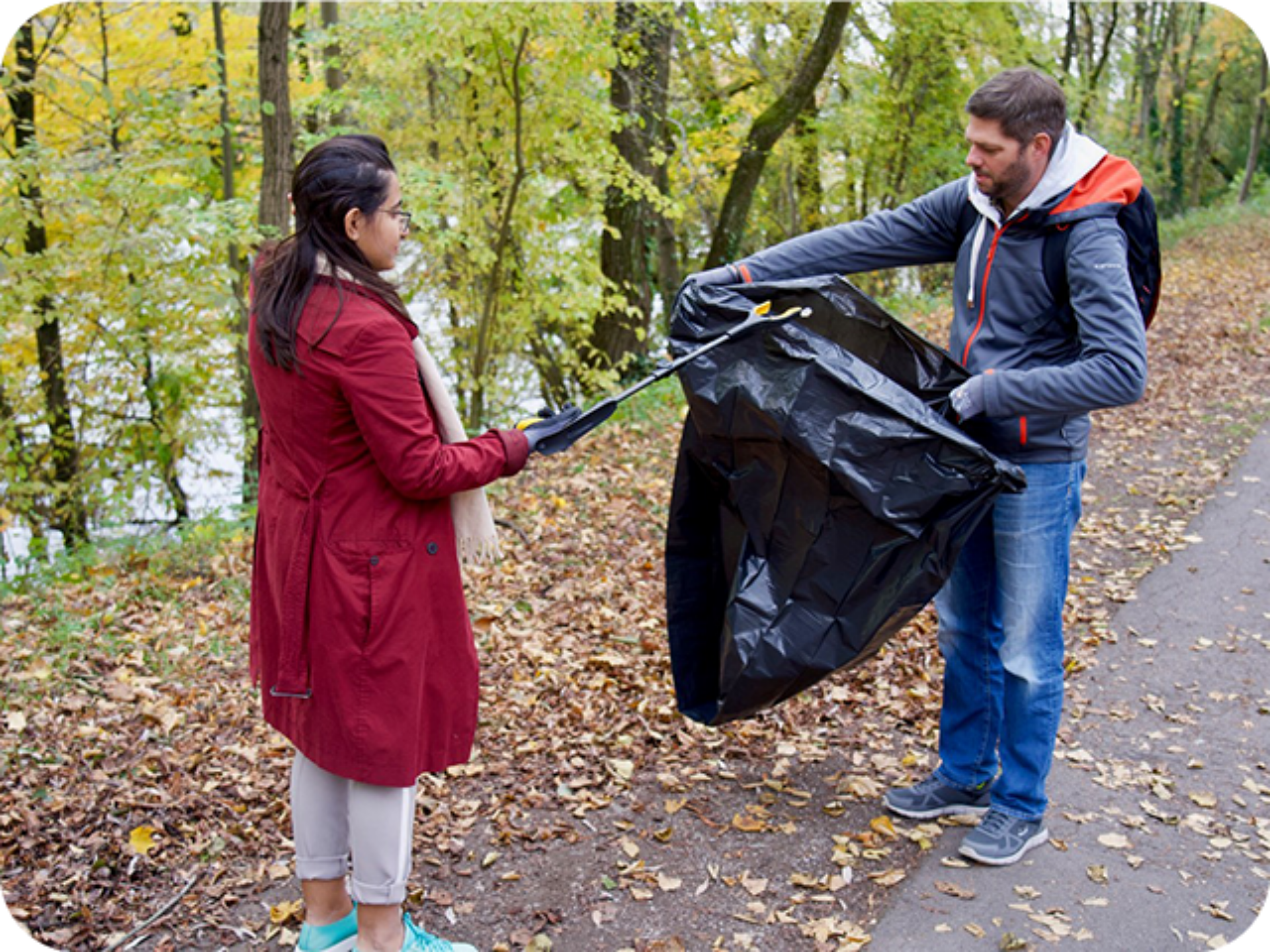 A man and woman engage in cleaning up litter in the woods, highlighting the importance of environmental stewardship.
