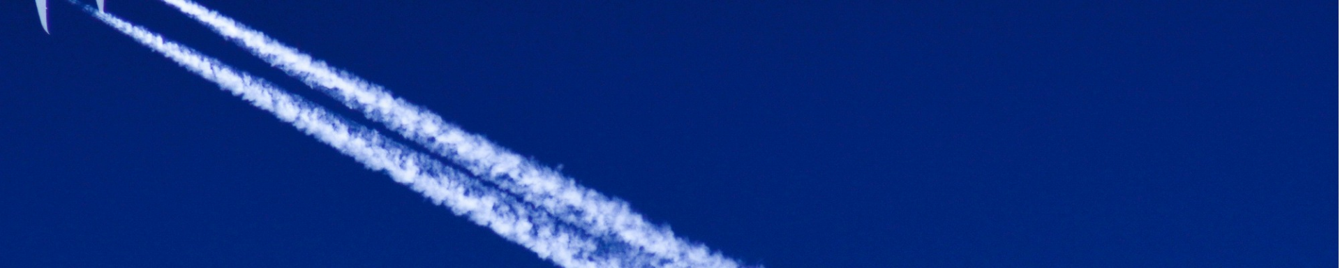 A jet aircraft ascends in the sky, creating a visible contrail as it moves swiftly through the atmosphere.