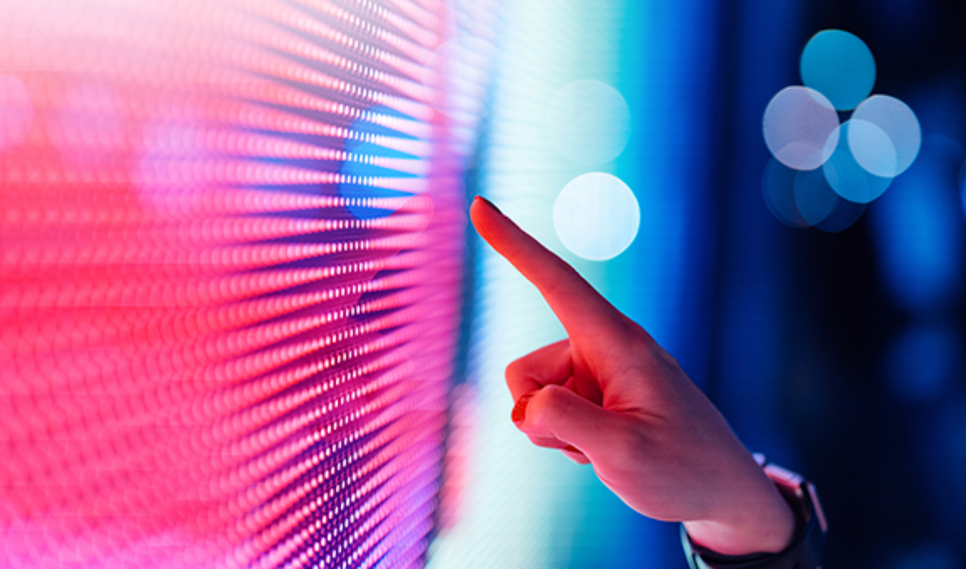 A person gestures towards a vibrant, colorful screen, highlighting its dynamic visual elements.